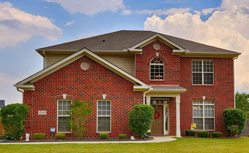 a large brick building with grass in front of a house