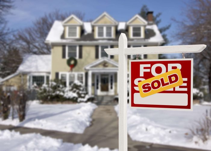 A Sign In Front Of A House Covered In Snow