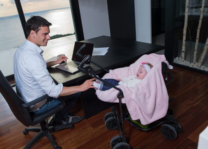 A Man Sitting At A Table Using A Laptop Computer